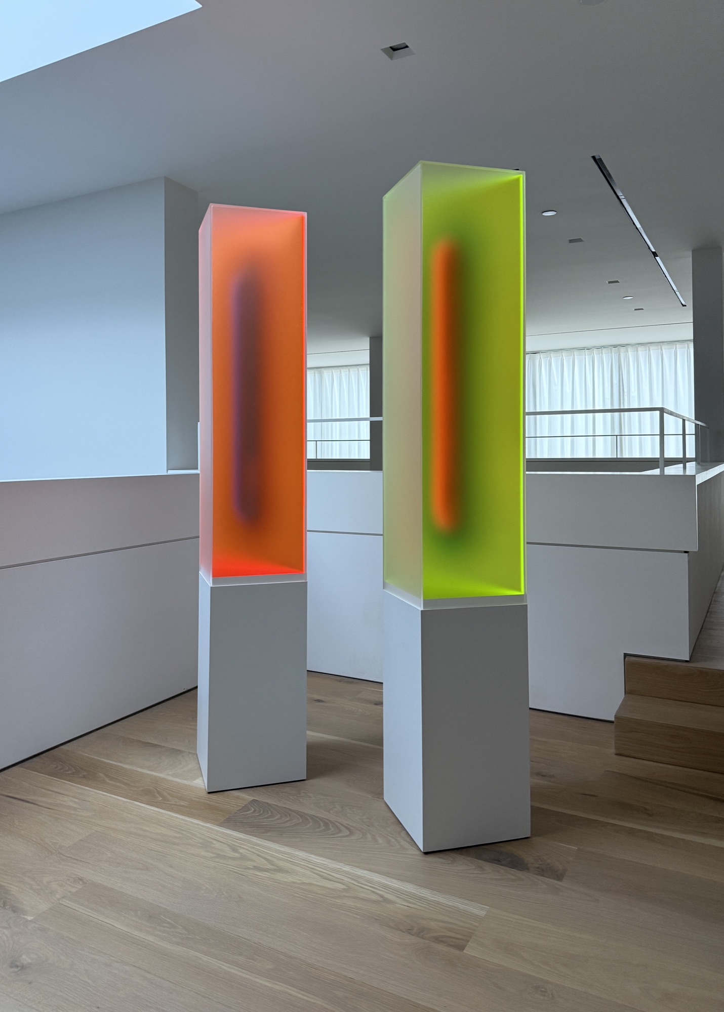Two standing Light Form columns in fluorescent orange and chartreuse acrylic on white pedestals